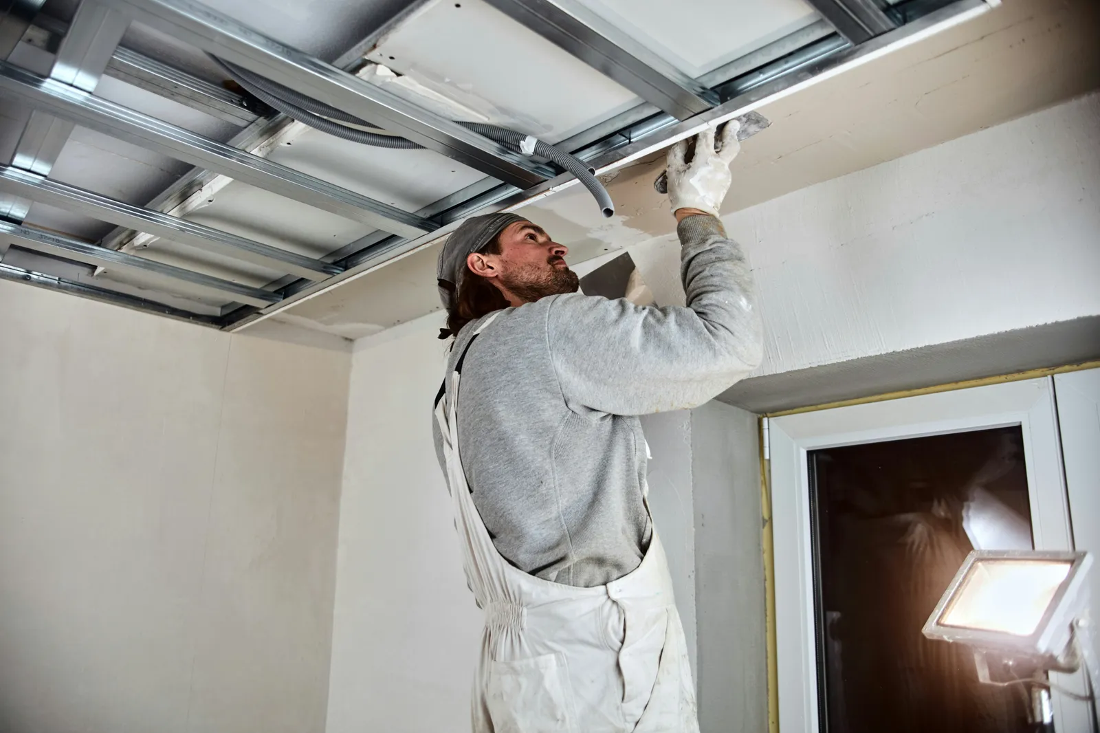 Trowel smoothing a fresh skim coat across a ceiling