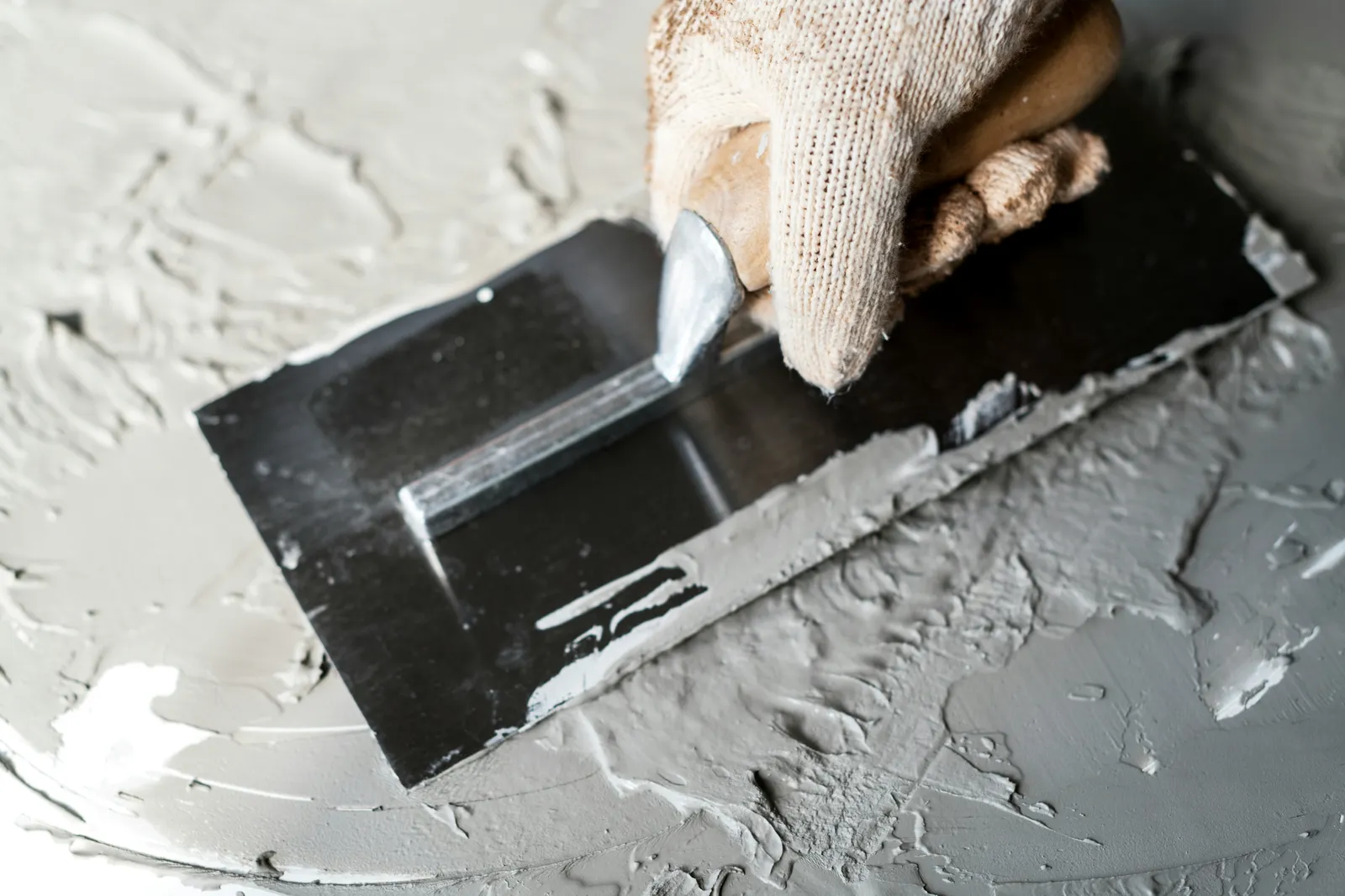 Plasterer filling and smoothing a damaged section of wall